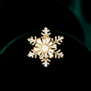 Rotating snowflake brooch with cubic zirconia and gold plating on green velvet