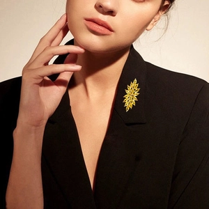 Eleganter goldener Blumen-Brosche mit gelben Kristallen am Revers eines schwarzen Anzugs