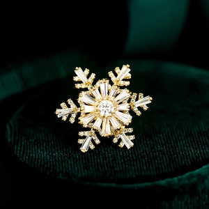 Close-up of golden rotating snowflake brooch with zircons on dark green velvet