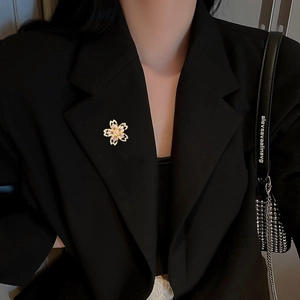 Broche fleur de cerisier avec zircons portée sur une veste blazer noire