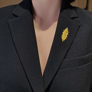 Makroaufnahme einer eleganten goldenen Zirkonia-Blumenbrosche an einem schwarzen Anzug