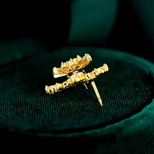 Macro shot of gold snowflake brooch with zircon crystals on dark green velvet