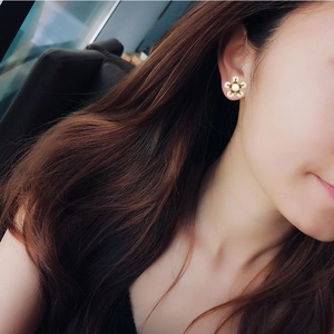 Élégantes boucles d'oreilles fleur à cinq pétales dorées avec perle blanche sur modèle