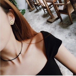 Boucles d'oreilles dorées en forme de fleur avec perle portées par un mannequin