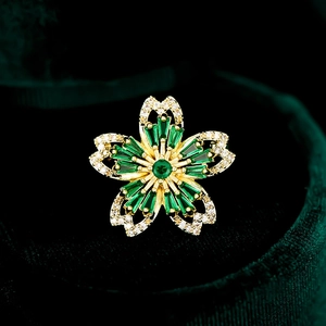 Vue détaillée d'une broche cerisier doré avec cristaux verts et zircons blancs