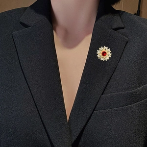 Broche fleur dorée élégante avec zircon rouge et cristaux radiants sur un costume noir