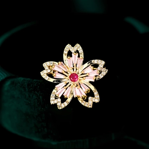 Détail de la broche fleur de cerisier en zircon rose avec base dorée et pierre rouge
