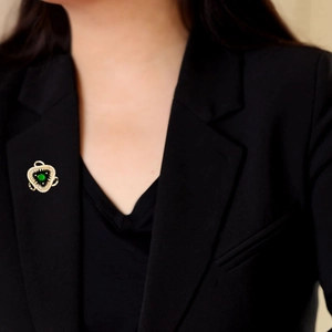Spilla di lusso a forma di scudo con pietra verde e zirconi su un blazer nero elegante