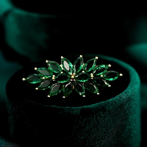 Makrodetail der eleganten Zirkon-Blumenbrosche mit grünen Steinen auf Samt