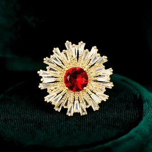 Gros plan détaillé d'une bague tournesol dorée avec pierre rouge et oxydes de zirconium