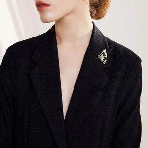 Elegant hollow gold butterfly brooch with white crystals on a black suit lapel