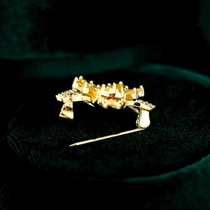 Vue latérale de la broche fleur de cerisier dorée avec zircons sur velours vert