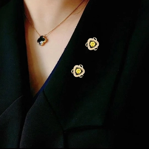 Dettaglio della collana a quadrifoglio e spille in zircone su un blazer nero