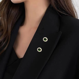 Detailansicht der Vintage-Broschen mit grünen Zirkonia am Revers eines Blazers
