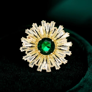 Macro de bague tournesol dorée avec pierre vert émeraude et pétales en zircon