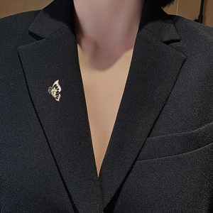Close-up of golden hollow butterfly brooch with sparkling crystals on black blazer lapel