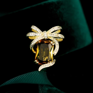 Luxury gold bow brooch featuring a large rectangular yellow crystal and pavé zircon stones