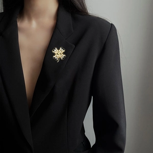 Elegant gold-plated four-leaf clover brooch with white zircons on a black blazer suit