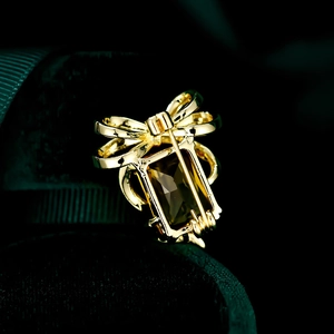 Macro shot of the gold bow pin back mechanism featuring a dark rectangular gemstone