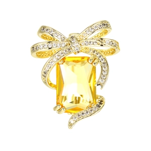 Luxury gold pin with rectangular yellow gemstone and diamond bow tie accent