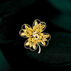 Macro shot of gold clover brooch with yellow marquise crystals and number five detail