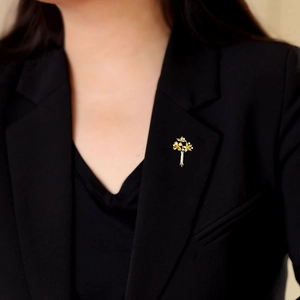 Élégante broche bouquet de fleurs dorée avec strass scintillants sur une veste de costume
