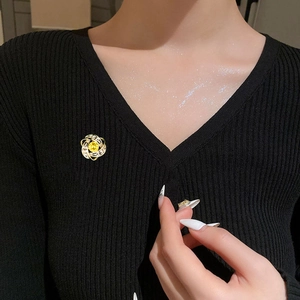 Dettaglio di elegante spilla a fiore con gemma gialla su tessuto a maglia nero