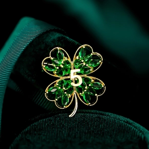 Macro shot of green clover brooch with golden number 5 detail on luxury velvet background