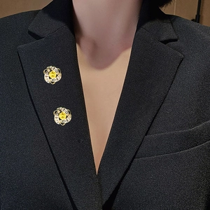 Dettaglio della spilla con zircone colorato su bavero nero per uno stile elegante