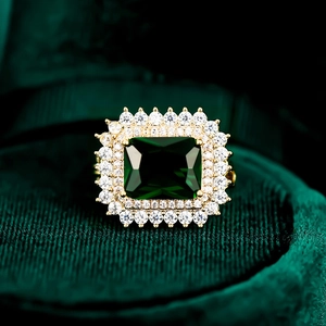 Anillo elegante con gema verde de corte esmeralda y doble halo en acabado dorado