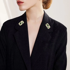 Vintage gold brooch set with emerald and sapphire stones on a black suit lapel