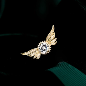 Détail d'une broche ailes d'ange dorées avec cristal central et oxydes de zirconium