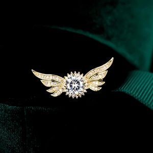 Détail de la broche aile dorée sertie de zircons sur support en velours foncé