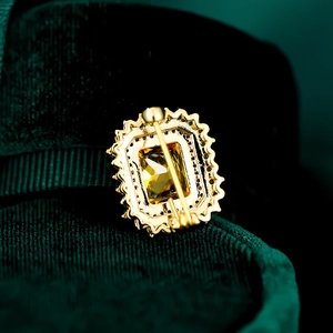 Detalle macro de broche vintage con piedra ámbar y bordes dorados con texturas