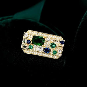 Close-up of vintage baroque brooch with emerald, sapphire, and zircon on green velvet