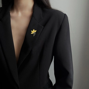 Elegant gold orchid brooch with white crystals pinned on a black blazer lapel