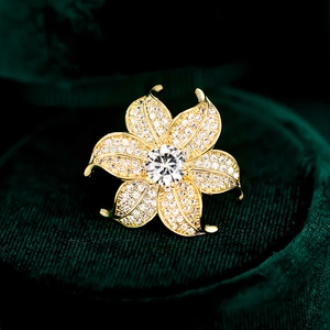 Luxury gold flower brooch with sparkling zircon petals on a green velvet background