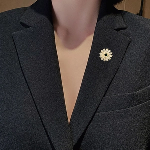 Nahaufnahme der goldenen Gänseblümchen Brosche mit Zirkonia und smaragdgrünem Stein auf Anzug