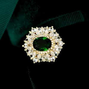 Makroaufnahme eines luxuriösen Goldrings mit großem ovalen grünen Edelstein und Diamanten
