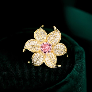 Macro detail of a gold flower brooch featuring white zircon petals and a pink center stone