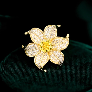 Macro detail of golden flower brooch with white cubic zirconia and yellow center stone