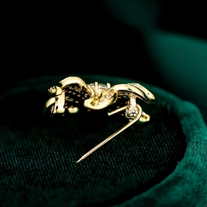Macro view of the golden brooch back showing a secure pin clasp on dark green velvet