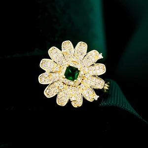 Makroaufnahme von Gänseblümchen-Ring mit grünem Stein und Diamanten auf Vergoldung