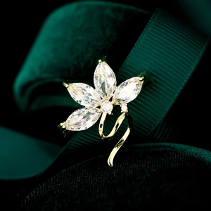 Macro view of gold orchid brooch with marquise cut zircons on dark green velvet
