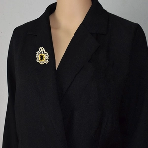 Detalle de broche vintage con gema amarilla y estrella plateada en solapa de blazer negro