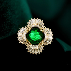 Macro view of luxury brooch with large emerald green stone and zircon fan details