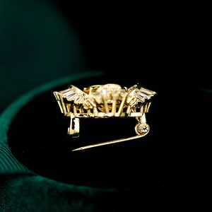 Close-up of golden brooch with micro-pave zircons and yellow gemstone on dark velvet