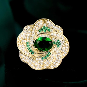 Vue macro détaillée de la bague fleur dorée avec pierre émeraude et pétales de diamants