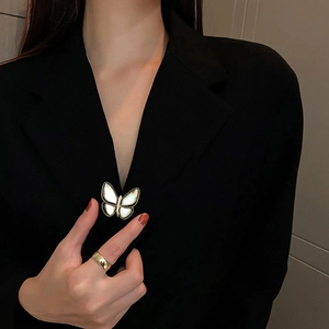 Detailansicht einer Schmetterling-Brosche mit Muschel-Inlay auf einem schwarzen Sakko