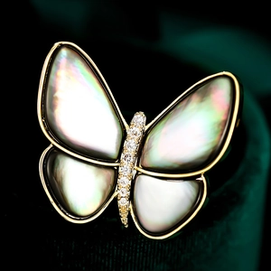 Makro-Detail der Schmetterlingsbrosche mit irisierenden Muschelflügeln und Zirkonia-Inlay